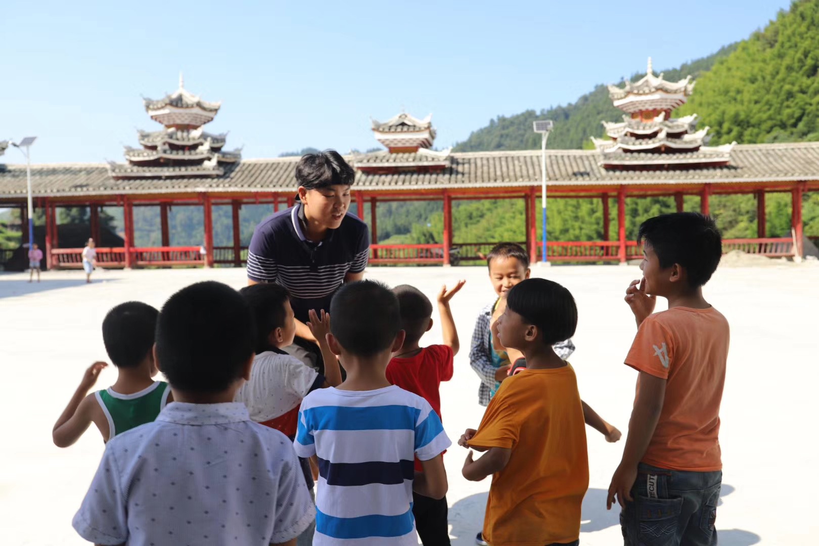 Oliver engaging a group of children outdoors during volunteer teaching